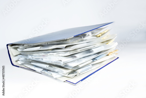 Large ring binder with clear punched pockets full of receipts, office management, accounting and tax calculation, light gray background, copy space, selected focus
