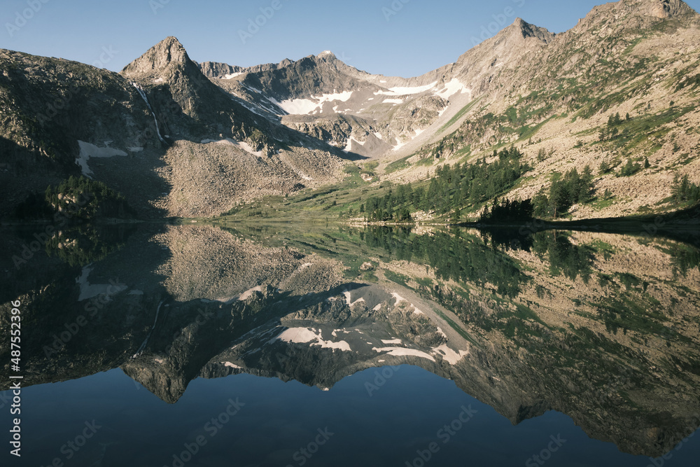 Mountain peak and its reflection in the lake in the highlands valley. Landscape photography of the Rocky shore of the Altai lake.