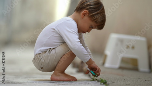 Child cutting green leaf with toy scissors © Marco