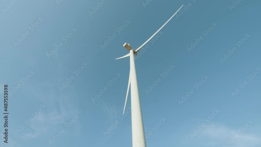 Close up of huge wind propeller working constantly on eco farm over blue sky. Concept of electric power production and clean energy. Large wind turbines with blades. Clean Renewable Energy. Close up of huge wind propeller working constantly on eco farm over blue sky. Concept of electric power production and clean energy. Large wind turbines with blades. Clean Renewable Energy.