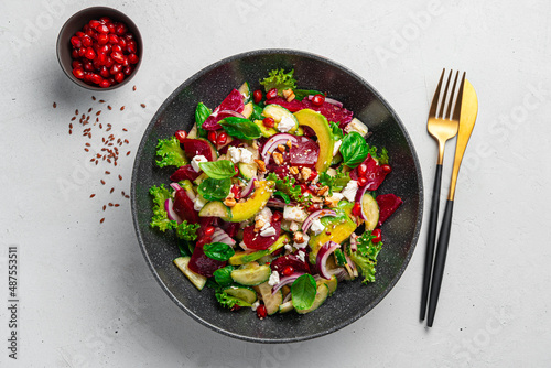 Fresh vegetable salad with beetroot, avocado and feta on a gray background.
