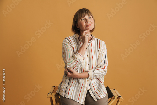 Senior woman wearing shirt looking aside while sitting on chair