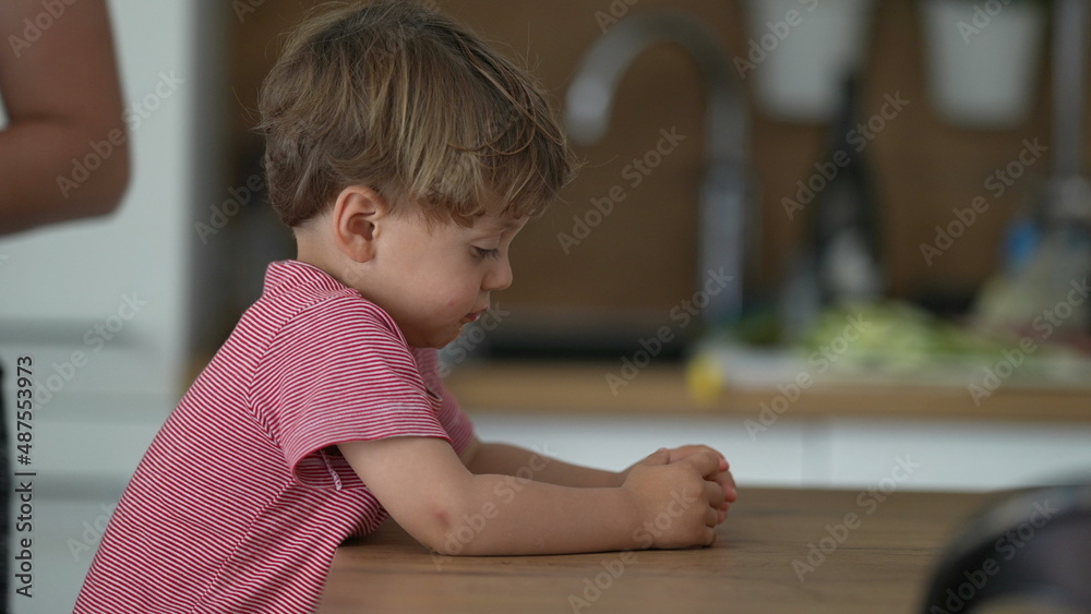 Bored little boy at home at kitchen table Bored little boy at home at kitchen table