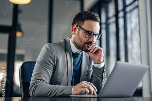 Concentrated caucasian businessman, focusing on his work, using laptop.