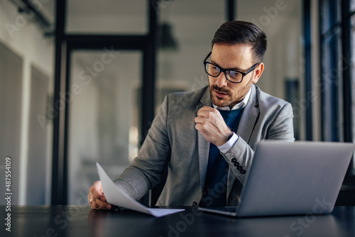 Hardworking caucasian man, reading a file, thinking what to do next.