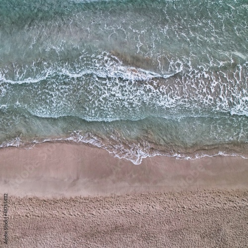 Foto aérea de la arena, mar y olas en Cala Llenya (Ibiza) tomada con dron DJI Air 2S