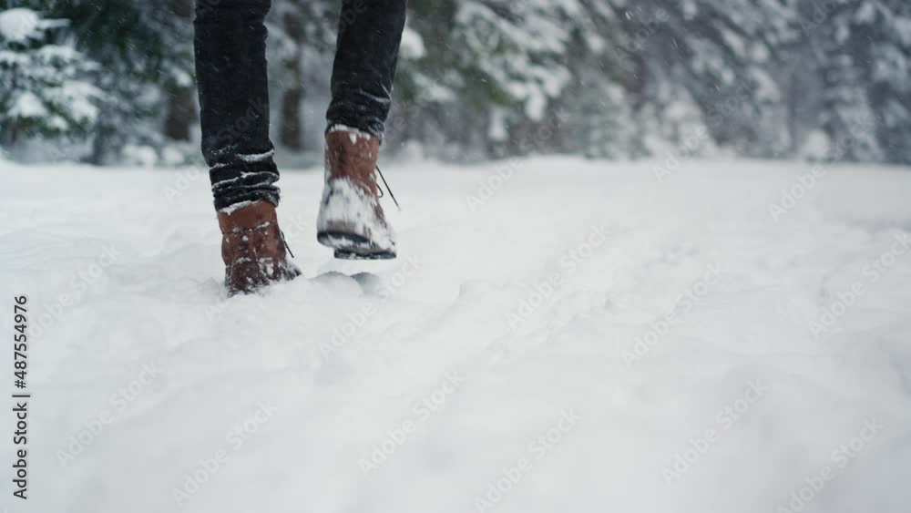 Low-section of unrecognizable man in winter boots walking along snowy path in wintery nature