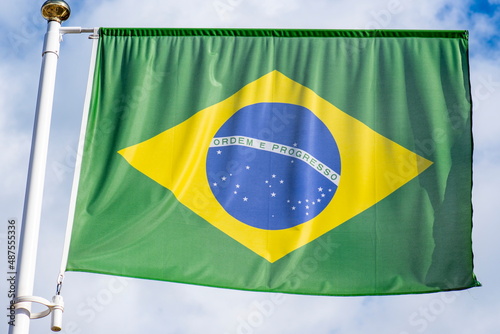 The flag of Brazil flutters in the wind in the center of the flag with the words order and progress