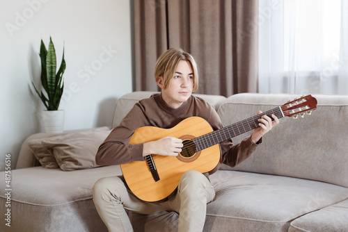 Handsome young guy hold acoustic instrumental guitar playing song