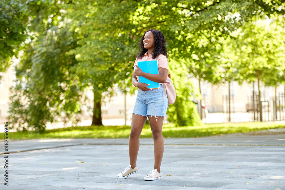 education, school and people concept - happy smiling african american student girl with notebooks in city education, school and people concept - happy smiling african american student girl with notebooks in city