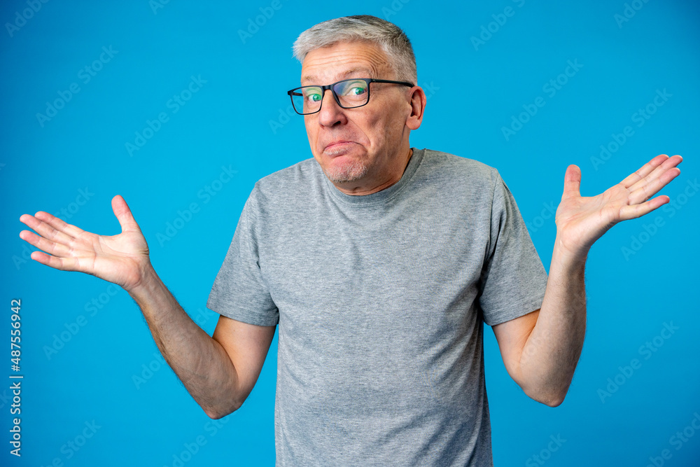 Naklejka premium Middle age man over blue background clueless and confused expression with arms raised