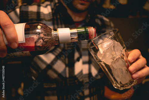 Male bartender hands pouring red liqueur into glass with ice © nazarovsergey