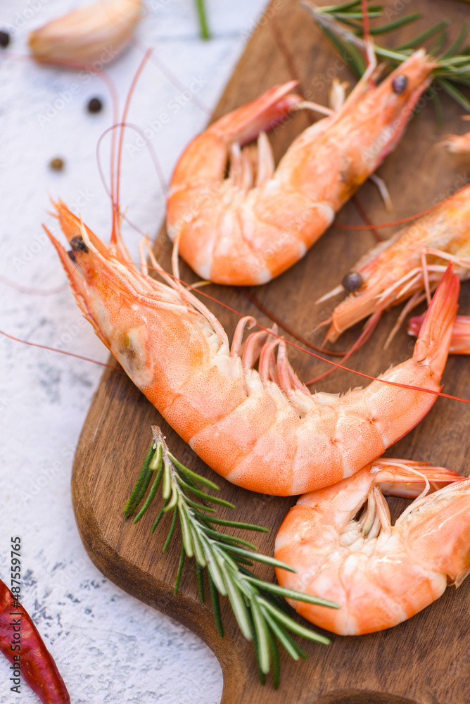 boiled shrimp prawns cooked in the seafood restaurant, fresh shrimps wooden cutting board plate with ice herbs and spices lemon chili rosemary on table background boiled shrimp prawns cooked in the seafood restaurant, fresh shrimps wooden cutting board plate with ice herbs and spices lemon chili rosemary on table background