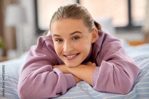 people concept - happy smiling girl lying on bed at home