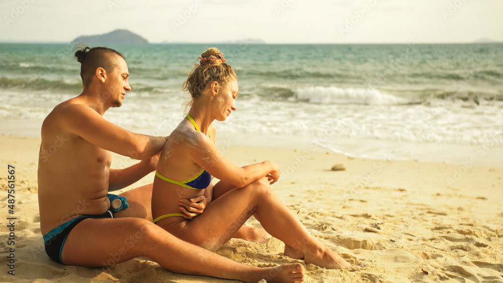 Hot sexy loving couple having sun block. Woman to put sunscreen man. Young girl and guy in hugging using sun cream. Concept rest tropical resort, traveling tourism happy summer holidays Hot sexy loving couple having sun block. Woman to put sunscreen man. Young girl and guy in hugging using sun cream. Concept rest tropical resort, traveling tourism happy summer holidays