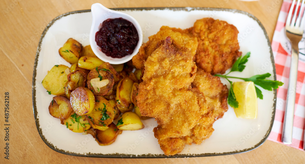 Saftiger Wiener Schnitzel vom Kalb mit wellen Panade und Bratkartoffeln auf schönem Teller Saftiger Wiener Schnitzel vom Kalb mit wellen Panade und Bratkartoffeln auf schönem Teller