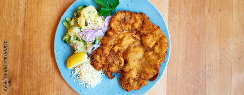 Saftiger Wiener Schnitzel vom Kalb mit wellen Panade und Bratkartoffeln auf schönem Teller 