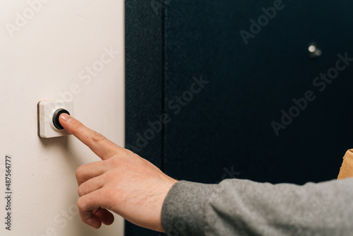 Photos Close-up finger of unrecognizable man pushing doorbell button in entryway of apartment building