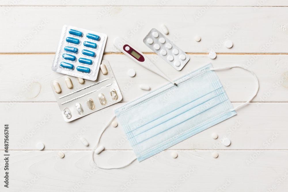 Protective face masks or surgical masks, medicine pills and thermometer on table background. Coronavirus disease. Corona virus concept. Space for text Protective face masks or surgical masks, medicine pills and thermometer on table background. Coronavirus disease. Corona virus concept. Space for text