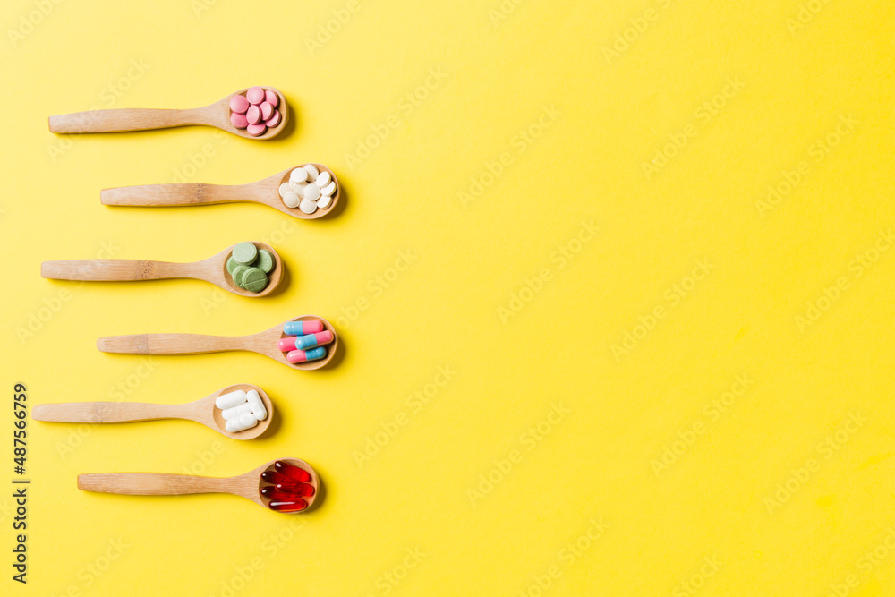 Top view Variety of vitamin and mineral pills in wooden spoon on Colored background. Top view of assorted pharmaceutical medicine pills. Dietary supplement healthcare product Top view Variety of vitamin and mineral pills in wooden spoon on Colored background. Top view of assorted pharmaceutical medicine pills. Dietary supplement healthcare product