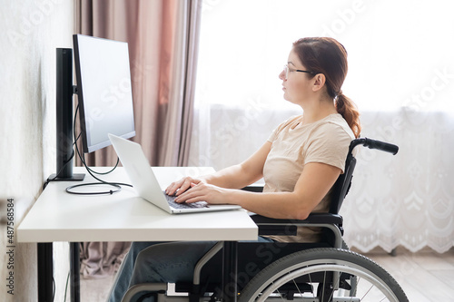 Caucasian woman on wheelchair working on laptop. 