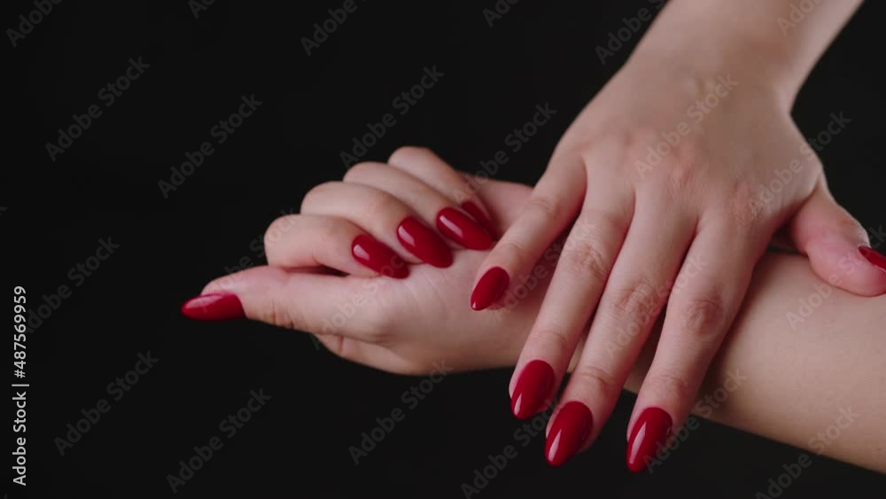 Crop woman with red nail polish. High angle of crop faceless female showing hands with red manicure against black background in studio