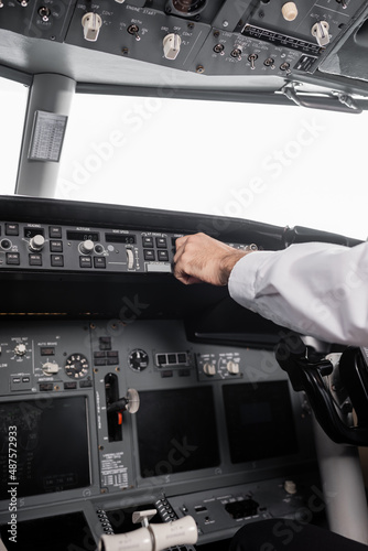 cropped view of pilot reaching control panel in airplane.