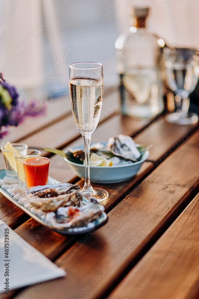 Fresh open oysters with a glass of chilled prosecco wine and set of shoot alcoholic cocktails served on table. Seafood delicios
