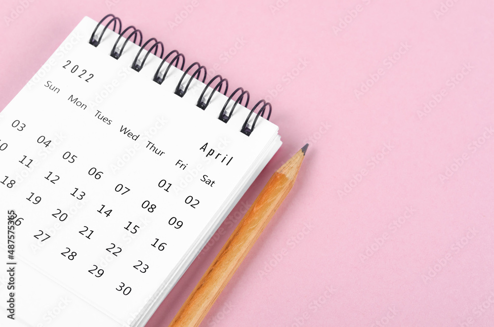 April 2022 desk calendar with wooden pencil on pink background. April 2022 desk calendar with wooden pencil on pink background.