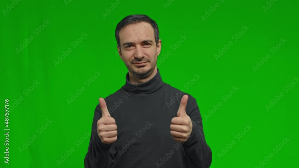 A man enthusiastically shows a thumb up with both hands over isolated green background A man enthusiastically shows a thumb up with both hands over isolated green background