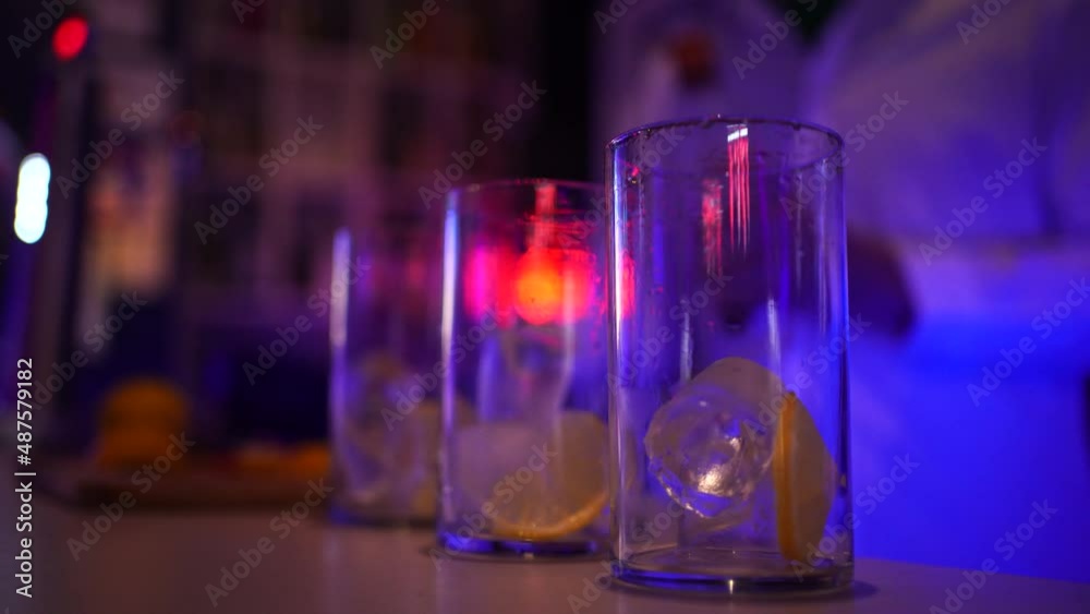Camarero de discoteca sirviendo copas detrás de la barra. El fondo es desenfocado con luces de neón rgb.