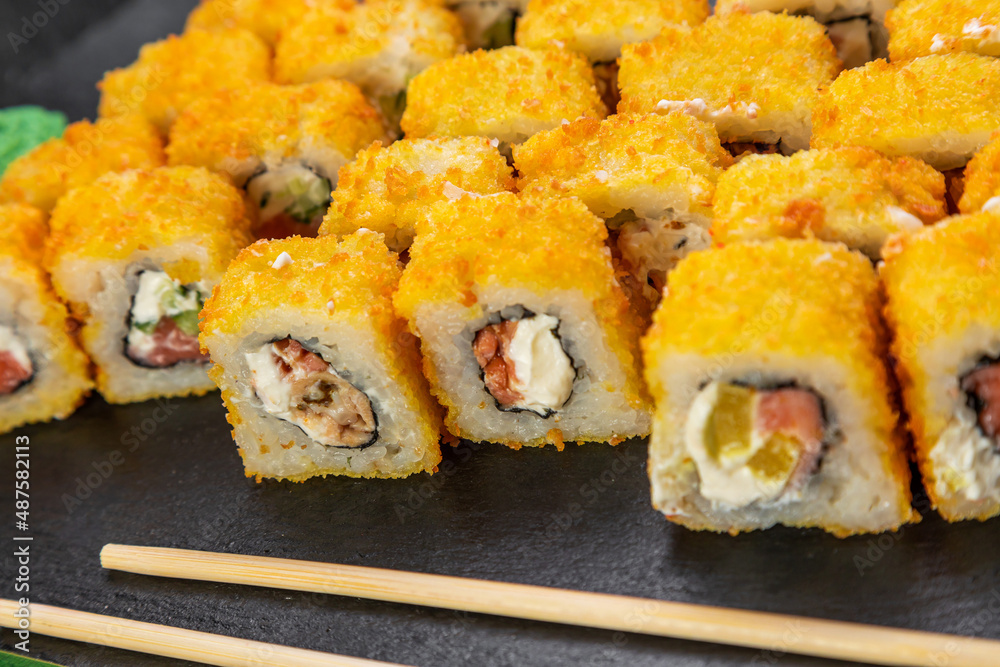 sushi rolls laid out on a dark background decorated with bamboo leaves and chopsticks sushi rolls laid out on a dark background decorated with bamboo leaves and chopsticks