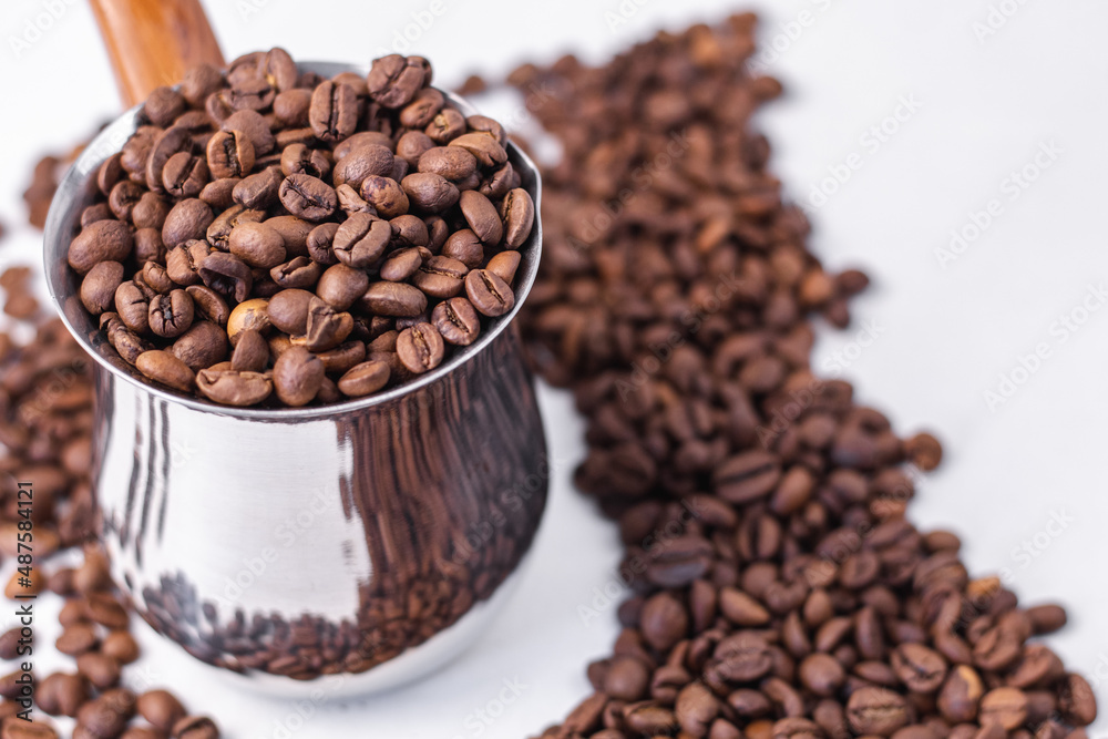 fragrant coffee beans stand on a white background in an iron coffee maker