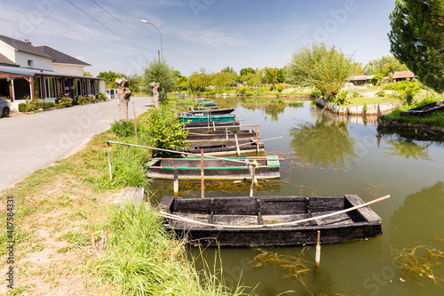 Fotomural Marais au coeur d'une ville, barques à fond plat amarrées le long d'un canal avec un restaurant devant