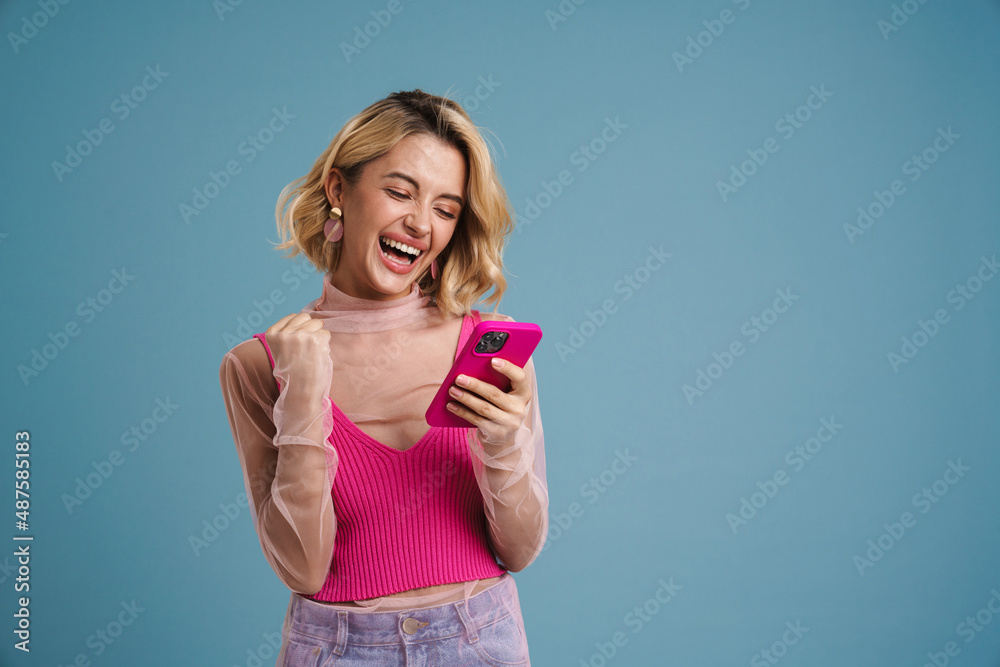 Young woman making winner gesture while using mobile phone Young woman making winner gesture while using mobile phone
