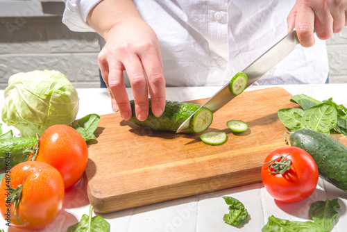 Close-up of cutting slicing fresh cucumbers. Womans hands cut with knife fresh cucumbers vegetables