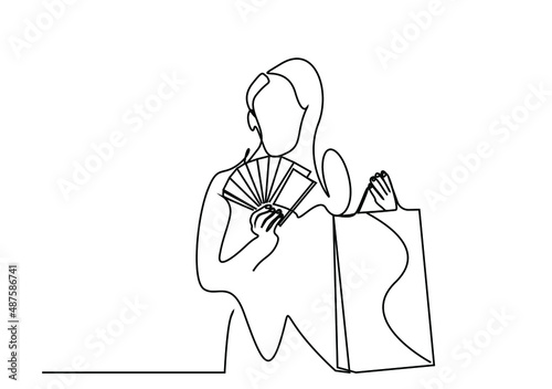 portrait concept of beautiful woman holding paper money in one hand and shopping bags in the other