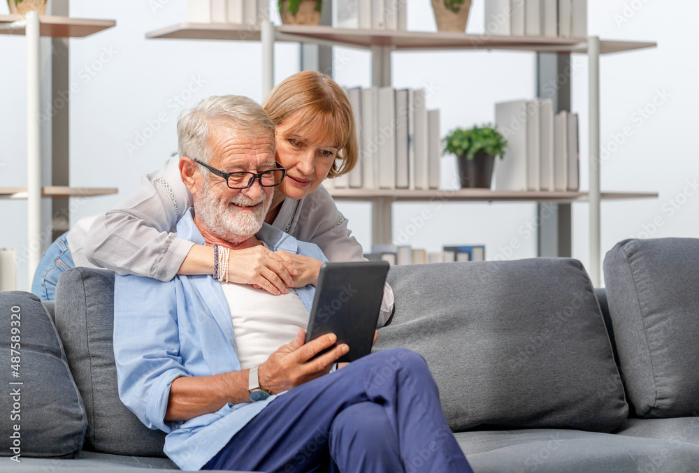Portrait of Cheerful senior couple in living room, Elderly woman and a man using smartphone talking on video call on cozy sofa at home, Happy family concepts