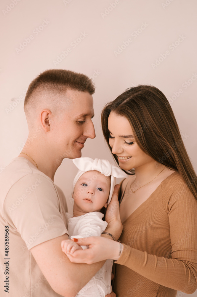Stylish young family, photographed with a little beautiful baby. The family expresses love and awe to each other. Family and parenting concept.