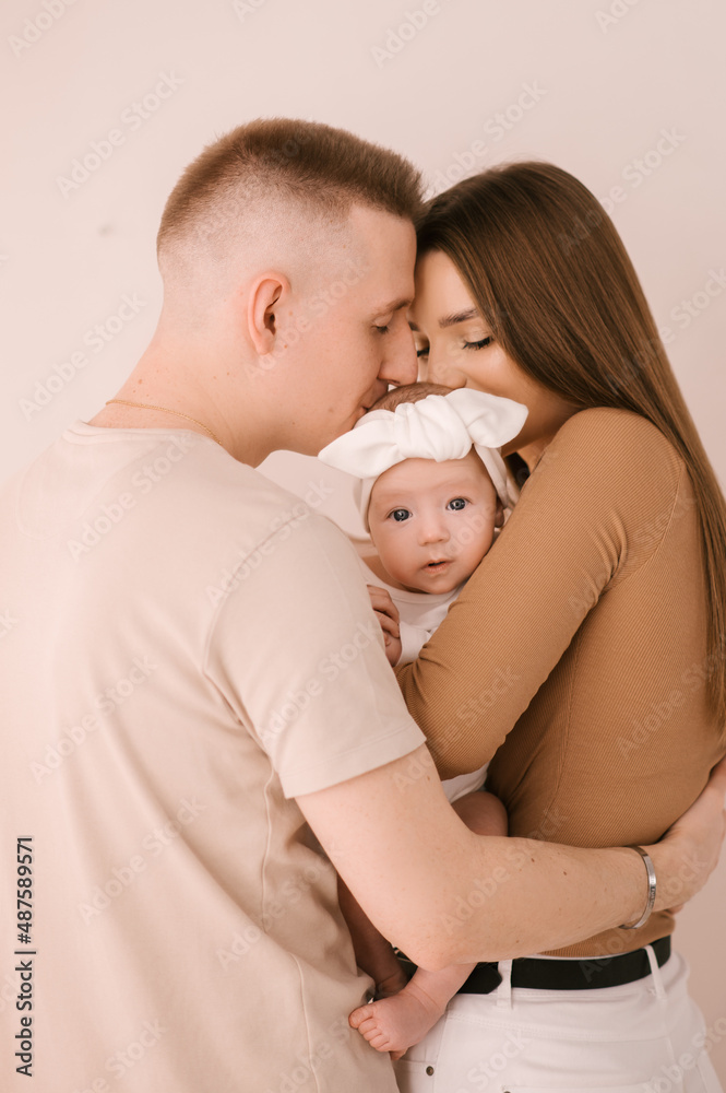 Stylish young family, photographed with a little beautiful baby. The family expresses love and awe to each other. Family and parenting concept.