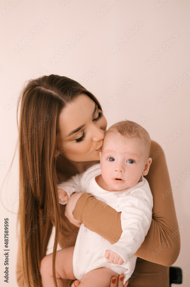Loving smiling young mother with her newborn daughter on a light background Loving smiling young mother with her newborn daughter on a light background