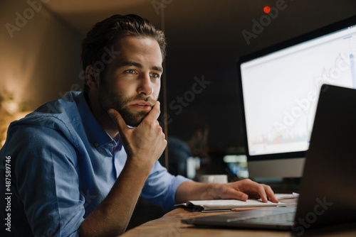 Foto Young man working with laptop and computer while sitting at desk