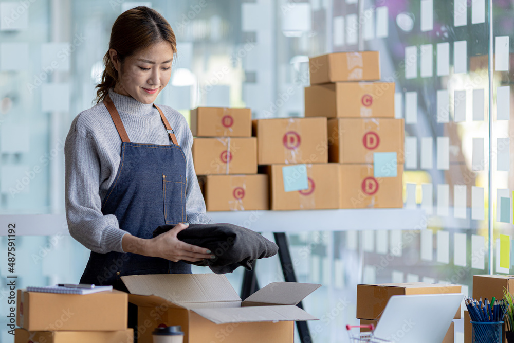 The owner of an online store is packing products into parcel boxes to prepare for delivery to customers according to orders through the website. Online selling and online shopping concepts. The owner of an online store is packing products into parcel boxes to prepare for delivery to customers according to orders through the website. Online selling and online shopping concepts.