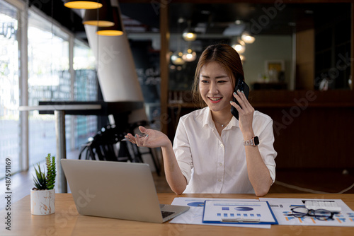 Wallpaper Mural Asian woman talking on the phone, she is a salesperson in a startup company, she is calling customers to sell products and promotions. Concept of selling products through telephone channels. Torontodigital.ca