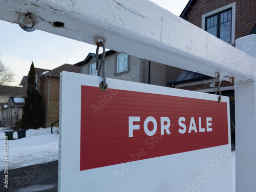 Sign for sale in front of a detached house in residential area. Real estate bubble, hot housing market, overpriced property, buyer activity concept
