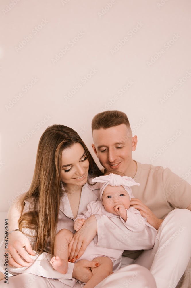 Stylish young family, photographed with a little beautiful baby. The family expresses love and awe to each other. Family and parenting concept. Stylish young family, photographed with a little beautiful baby. The family expresses love and awe to each other. Family and parenting concept.