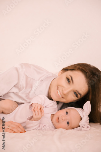 Loving smiling young mother with her newborn daughter on a light background