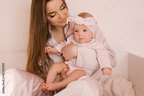 Loving smiling young mother with her newborn daughter on a light background