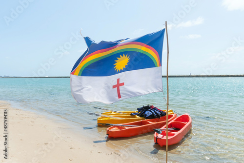 Pernambuco state flag waving with the wind at Muro Alto beach, a famous beach of Porto de Galinhas, Ipojuca city, Brazil. Beach tourist destination on the northeast coast. photo