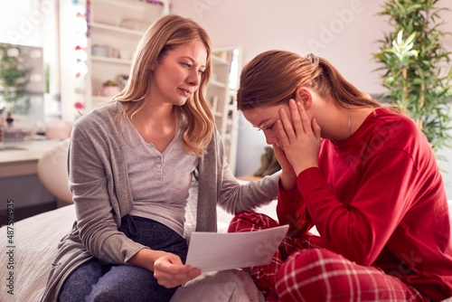 Fototapet Disappointed Teenage Daughter Wearing Pyjamas Looking At School Exam Report With